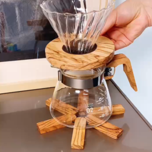 Hand holding an olive wood V60 glass coffee dripper