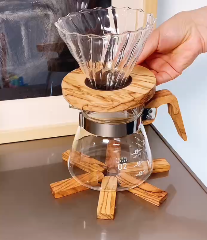 Hand holding an olive wood V60 glass coffee dripper