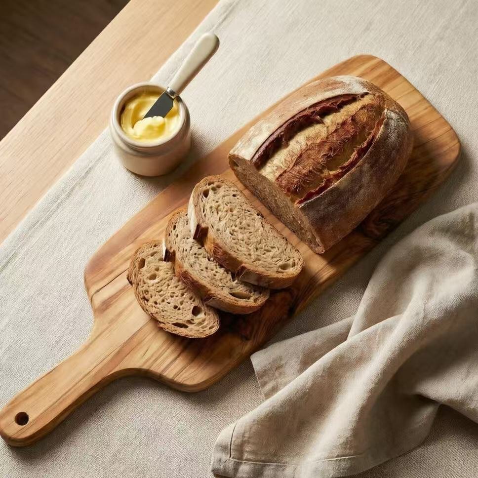 Olive wood bread board with handle serving sliced artisan bread and butter